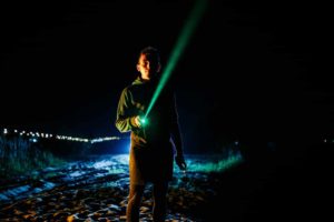 man pointing a green laser pointer toward the sky