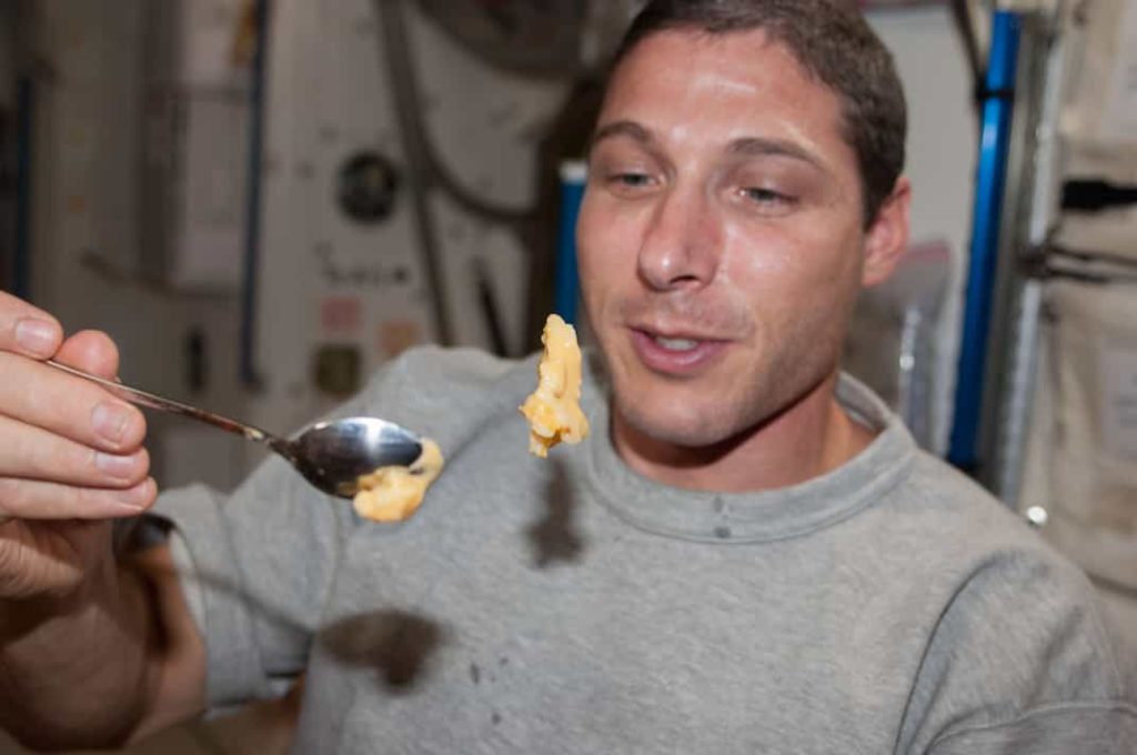 astronaut attempting to eat solid food