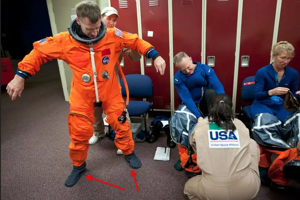 astronaut putting on a ACES suit