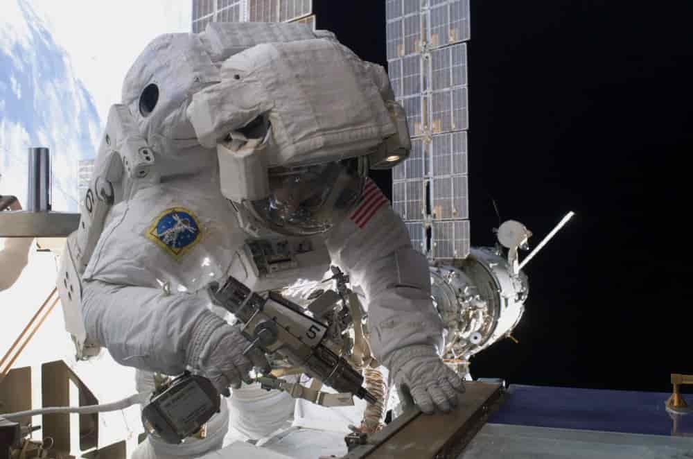 astronaut using tool during spacewalk