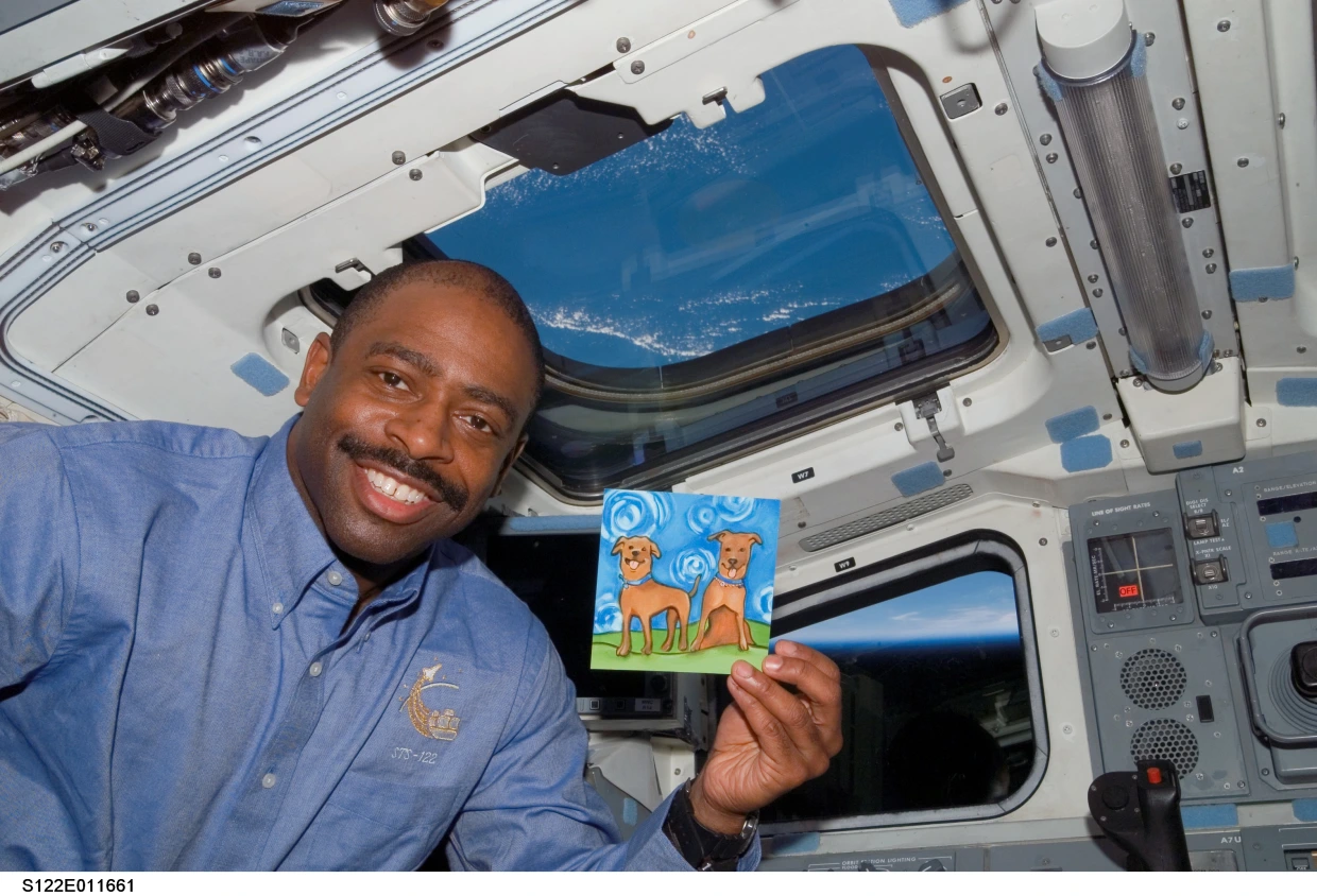 astronaut holding drawing of his dogs in space