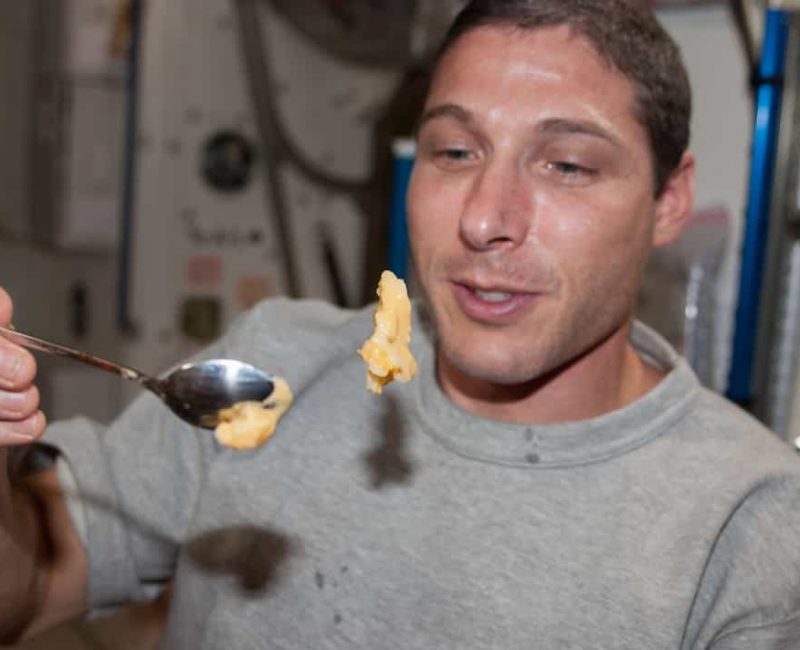 astronaut attempting to eat solid food