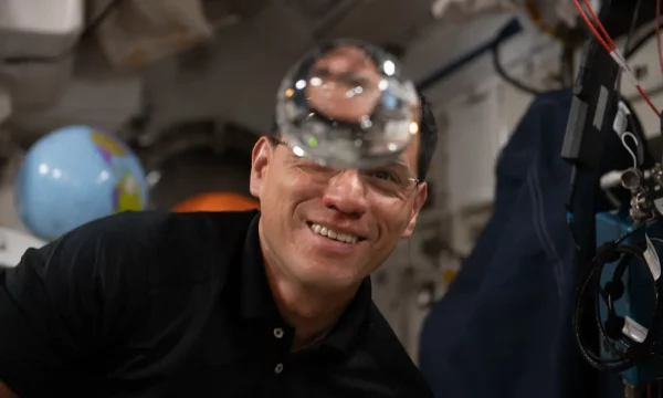 astronaut looking at floating bubble of water