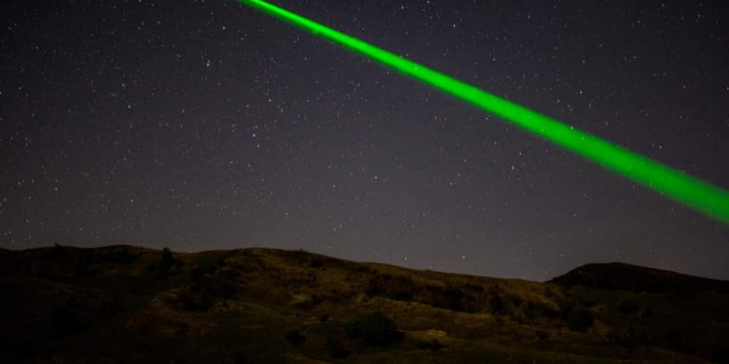 green astronomy laser pointer on starry sky