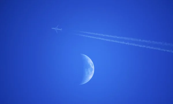 plane flying by the moon during the day
