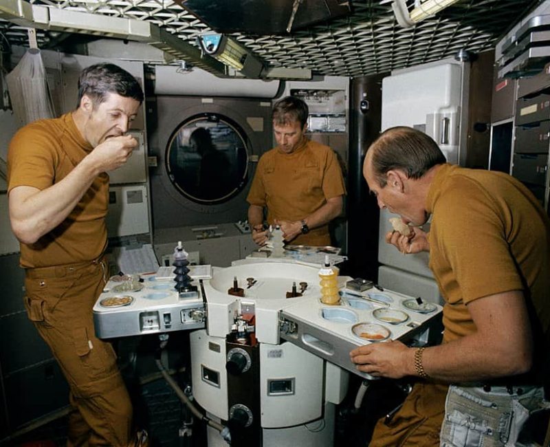 three astronauts enjoying their space meal